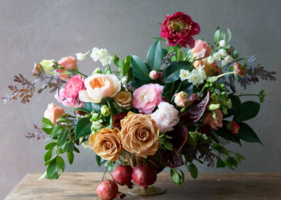 pomegranite, roses, peonies and other flowers and greens in pedestal container