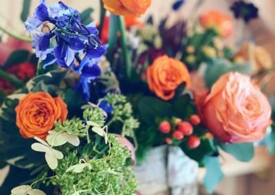 bright orange and blue flowers in a birch wood container