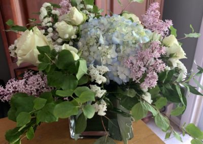 hydrangea, lilacs and rose with greens arranged in glass square vase