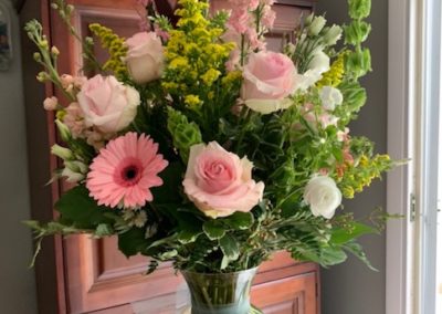 pink white and yellow flower arrangement in glass vase