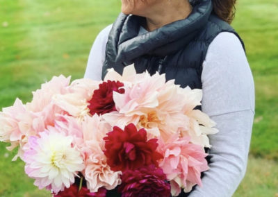 woman carrying bucket of bright pink and red peonies