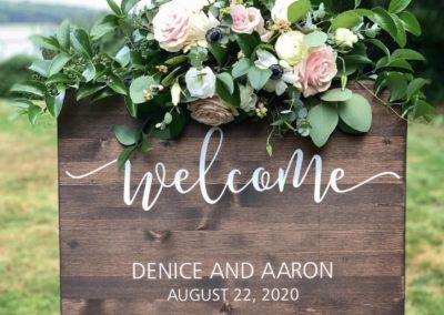 greenery and roses on wooden welcome wedding sign