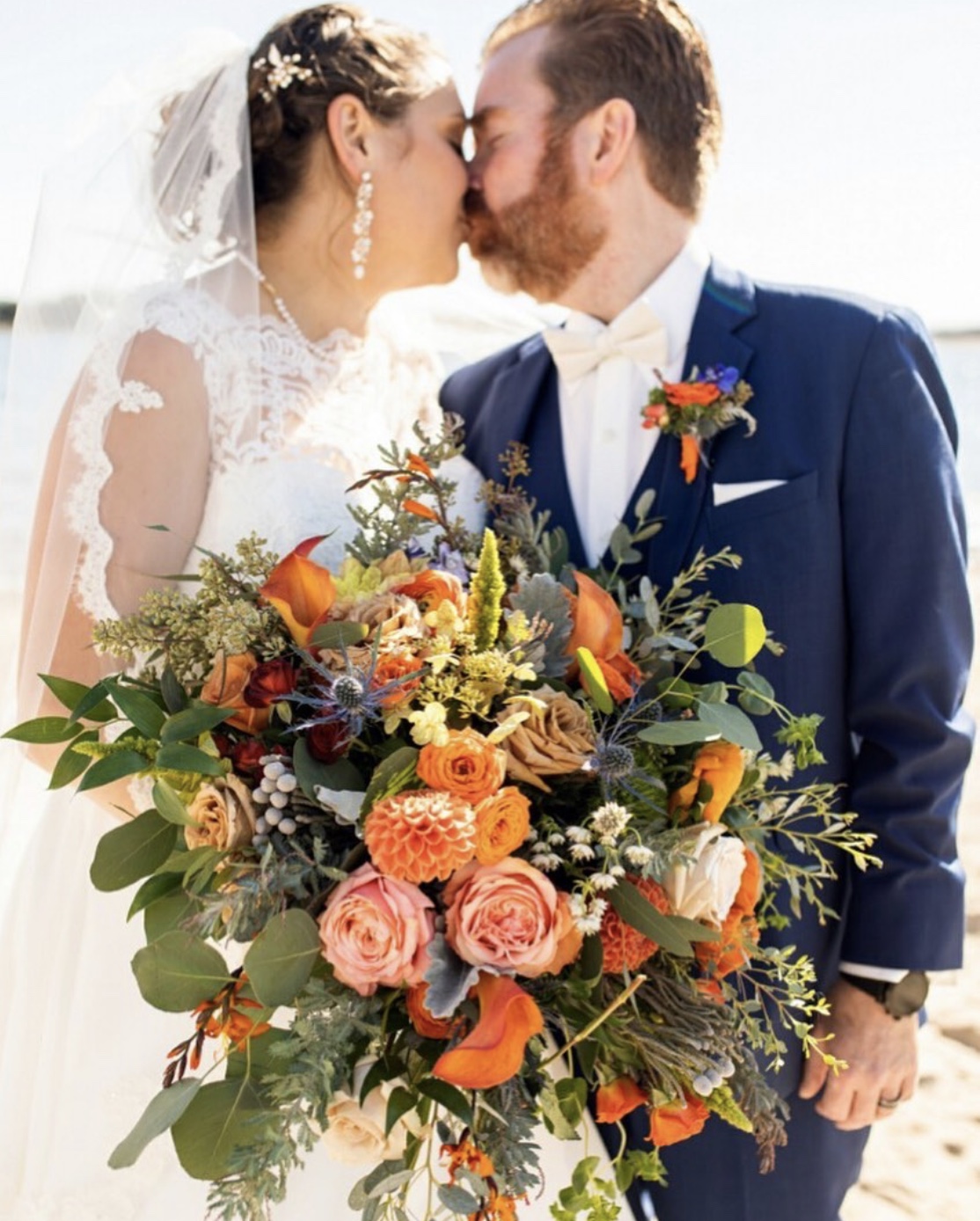 orange wedding bouquet with bride and groom